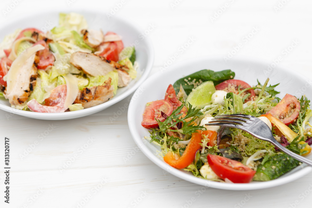 white deep plates with fresh salad ingredients mixed with sauce placed on an attractive background. A place for a menu, banner or advertisement white deep plates with fresh salad ingredients mixed with sauce placed on an attractive background. A place for a menu, banner or advertisement
