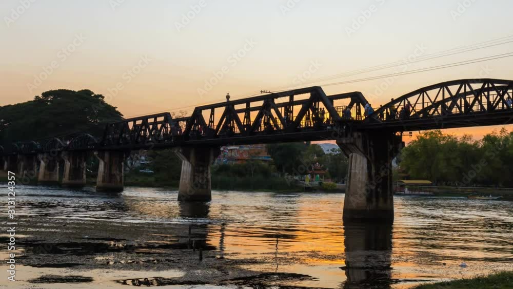 Time lapse of Bridge over the River Kwai day to night with tourists walking on the bridge. Is an important landmark and a tourist destination