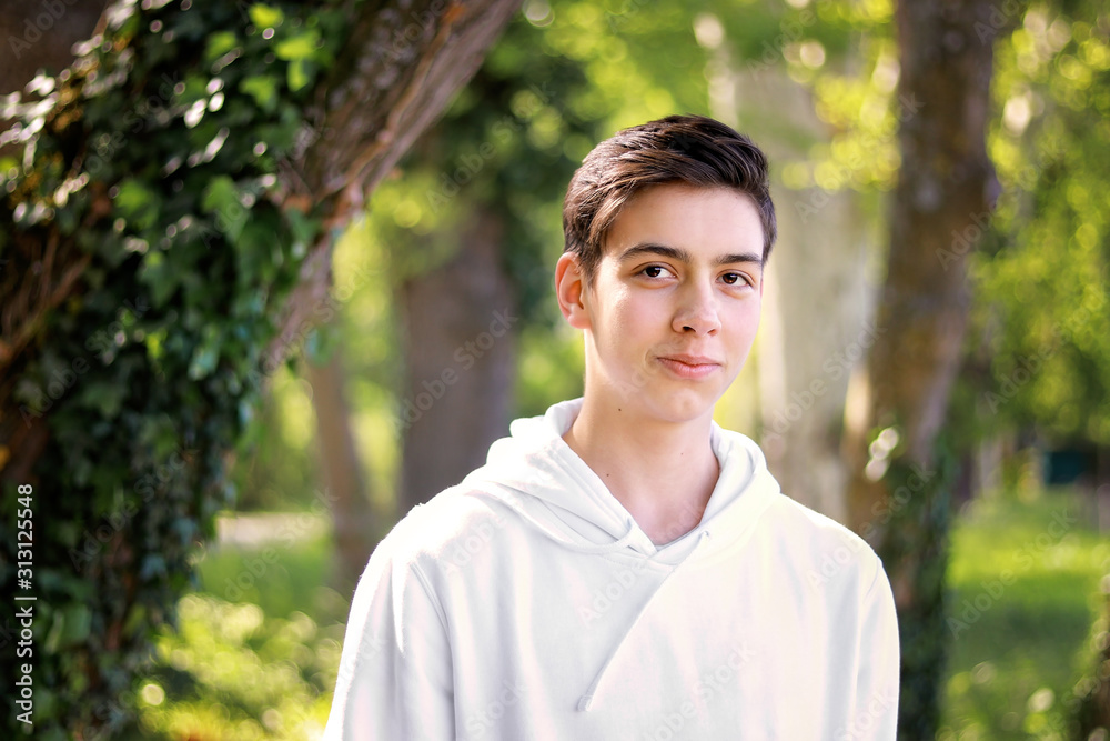 Portrait of handsome shy teenager boy in park outdoors. Natural light. Adolescent boys Portrait of handsome shy teenager boy in park outdoors. Natural light. Adolescent boys