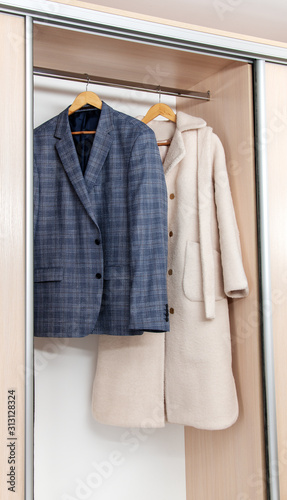 Men's suit and women's coat in the wardrobe closeup