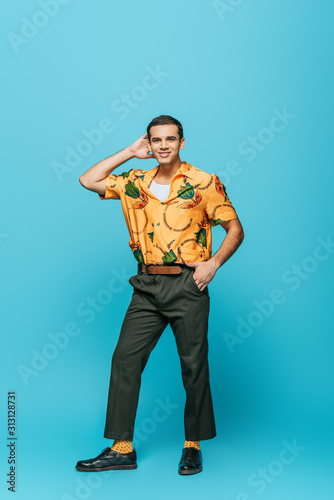 handsome dancer looking at camera while dancing boogie-woogie on blue background