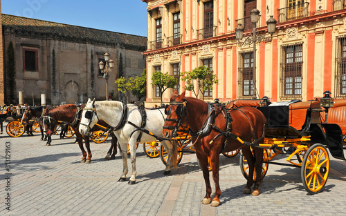 Horse carriages and Archbishop's Palace in the Virgin of the Kings (Virgen de los Reyes) Square in Seville, Andalusia, Spain