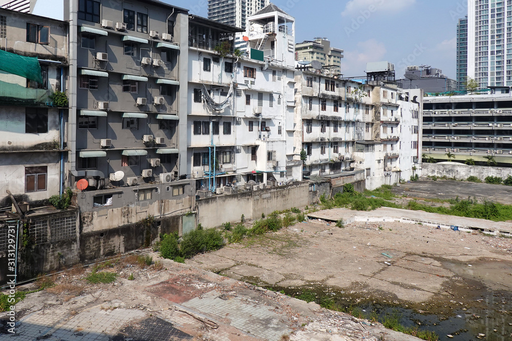 Fototapeta premium Dirty concrete backyard and old apartment building wall with many air conditioner