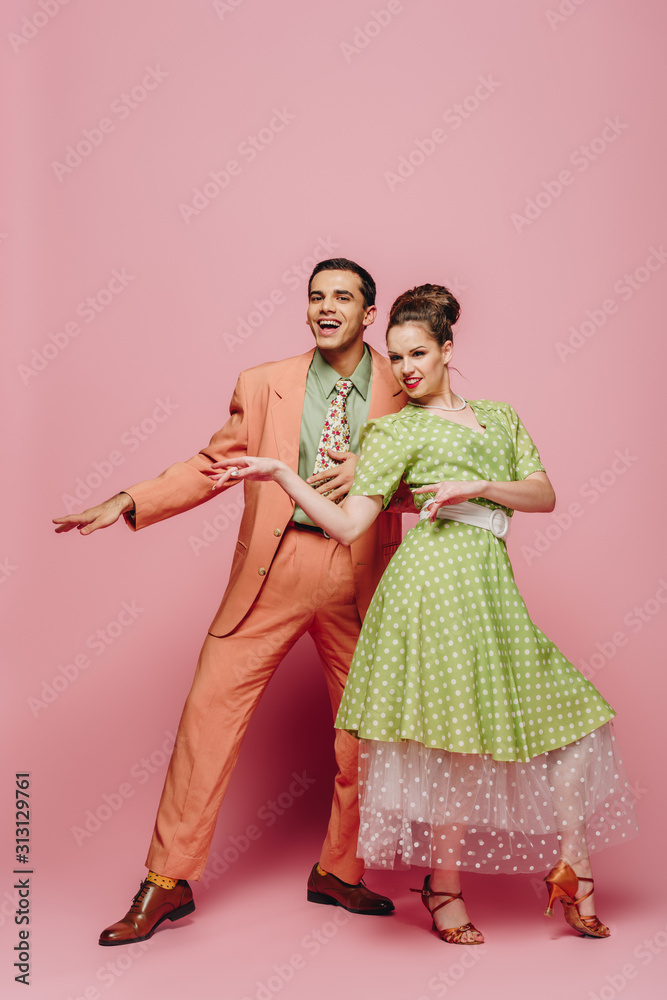 cheerful dancers looking at camera while dancing boogie-woogie on pink background cheerful dancers looking at camera while dancing boogie-woogie on pink background