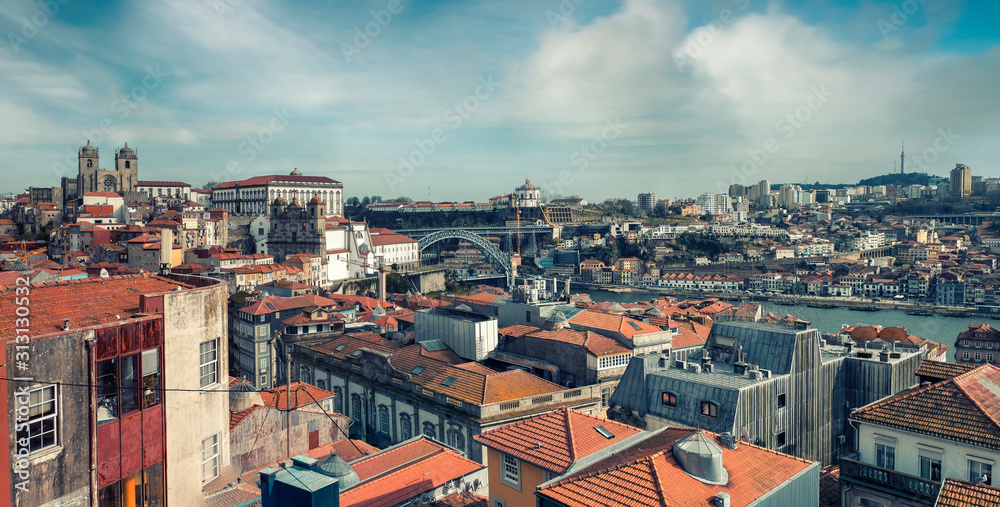 Panorama of the historic center with red tile roofs and the Don Luis Bridge in Porto Portugal a sunny spring day