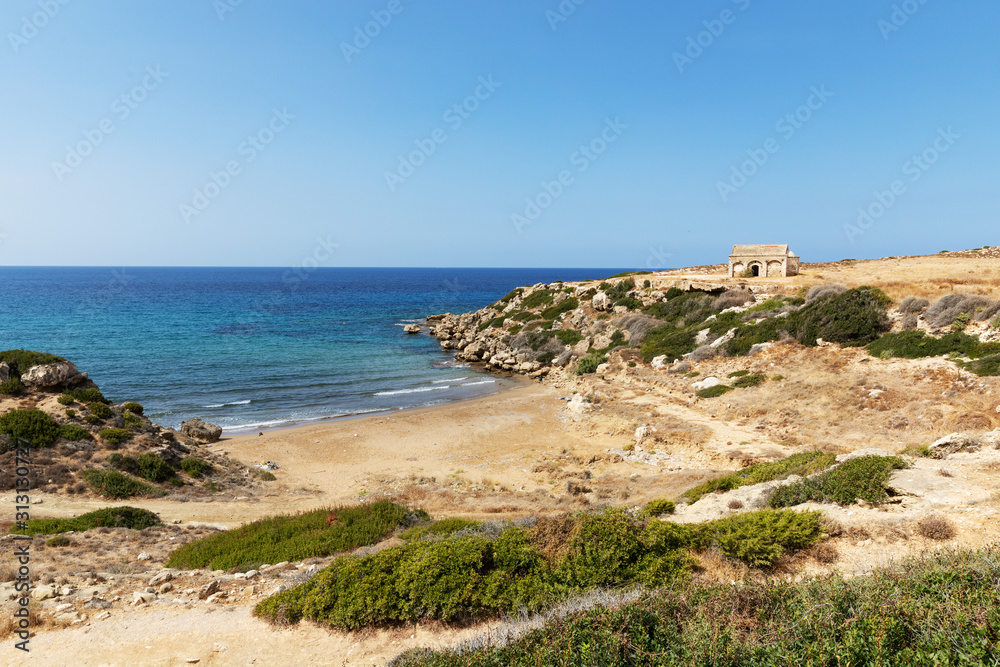 Mediterranean Sea in Northern Cyprus. The ruins of an ancient building on the island. Summer seashore with transparent blue water. Seascape. Skyline. Beauty of the planet