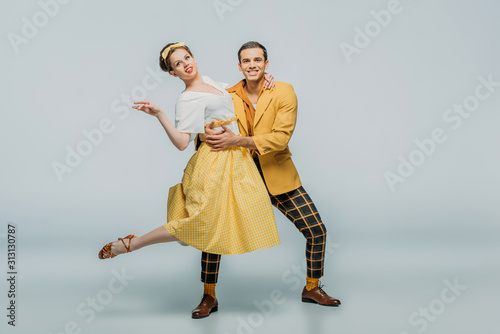 smiling dancers looking at camera while dancing boogie-woogie on grey background photo