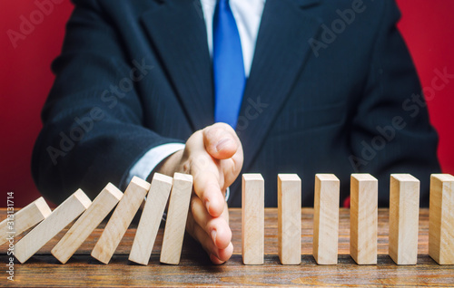 Businessman stops domino falling. Risk management concept. Successful strong business and problem solving. Reliable leader. Stop the destructive processes. Strategy development. Debt restructuring photo