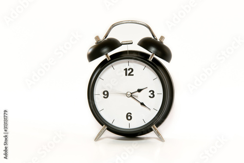 Vintage alarm clock with simple and minimalist design, isolated on white background. Secong hand moving, concept of time passing.