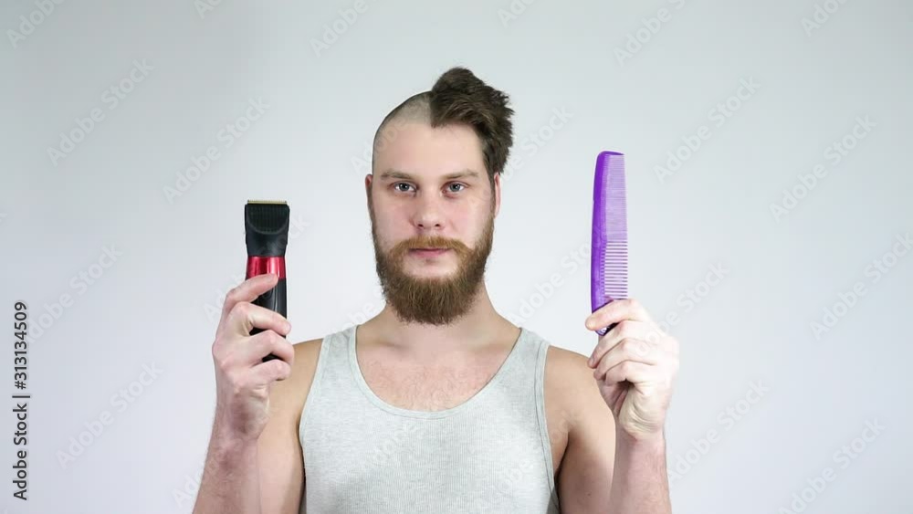 Half shaved man holding a clipper and a comb.The concept of before and after. Half shaved man holding a clipper and a comb.The concept of before and after.