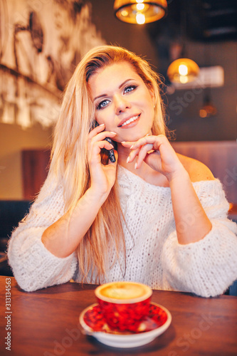 Playful flirty charming blonde in a cafe at a table talking on the phone
