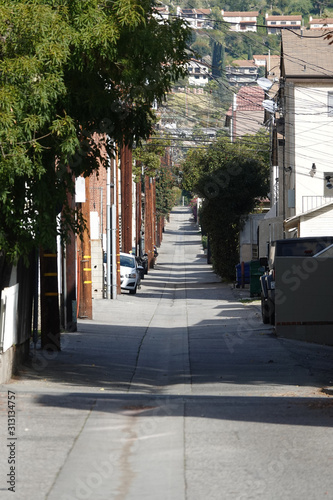 Fototapeta Naklejka Na Ścianę i Meble -  An urban alley roadway between apartment buildings in California is shown during the day in the late 2010s.