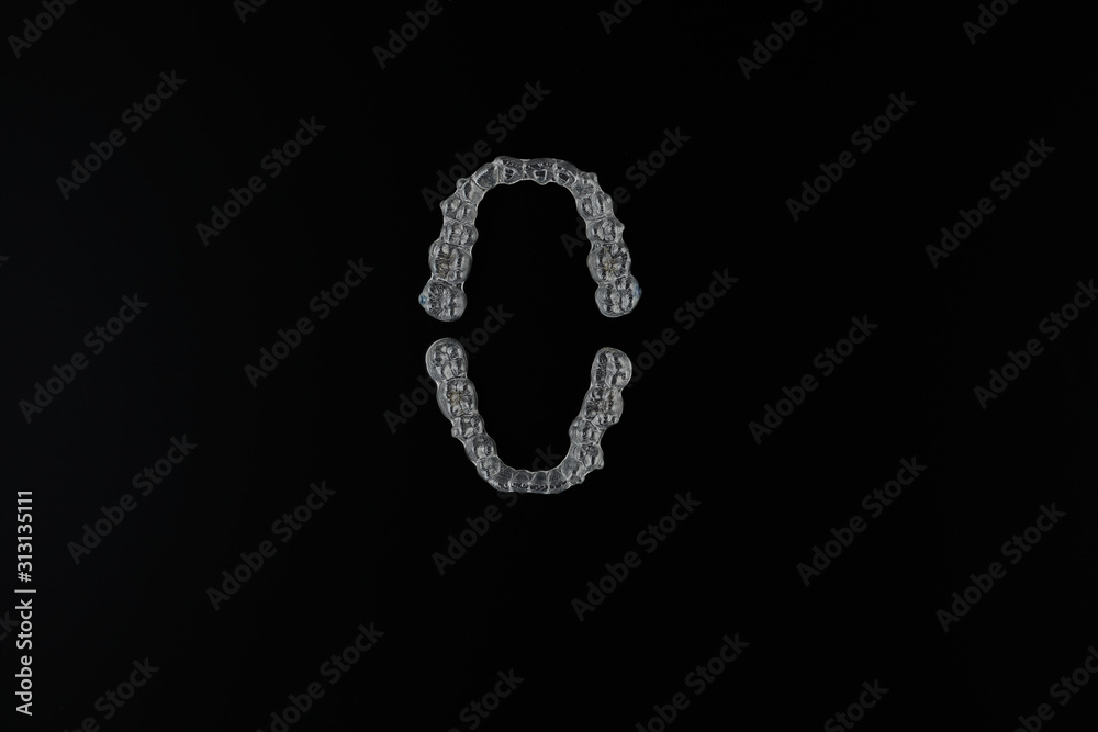 Top view of invisalign braces or invisible retainers on black background, new orthodontic equipment for bite correction. New bite treatment technologies.