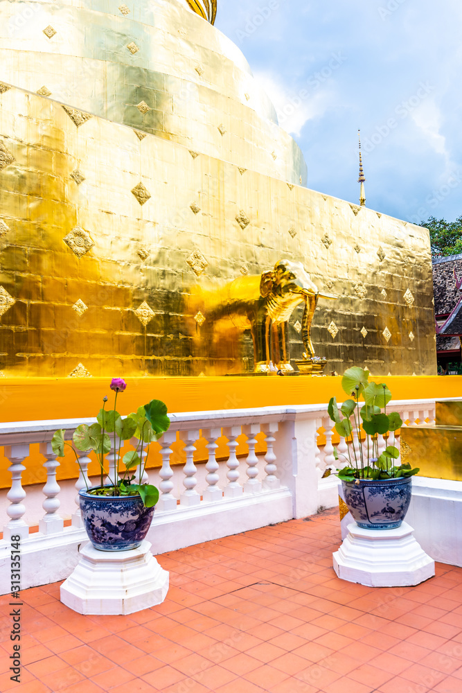 Fototapeta premium Golden statue of elephant placed on Wat Phra Singh temple in Chiang Mai,Thailand. Beautiful buddhist symbol, famous tourist destination. Ancient sculpture in small parkland. Religion and spirituality