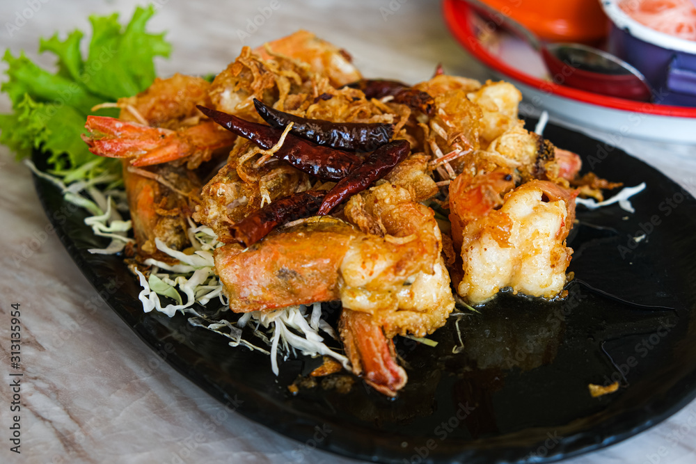 shrimp with tamarind sauce thailand seafood. Sweet and sour tasty food. decorative with vegetable and red hot chilli on black plate.