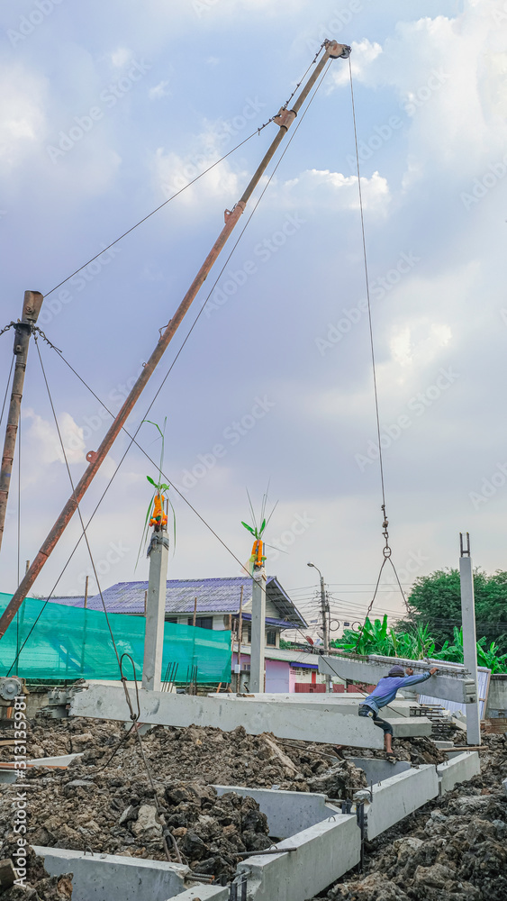 worker man use high tripod rid move cement beam for make foundation pile. building new house in city worker man use high tripod rid move cement beam for make foundation pile. building new house in city