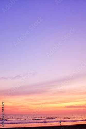 Silhouette Of Man Walking Towards The Ocean During Beautiful Sunset At The BEach