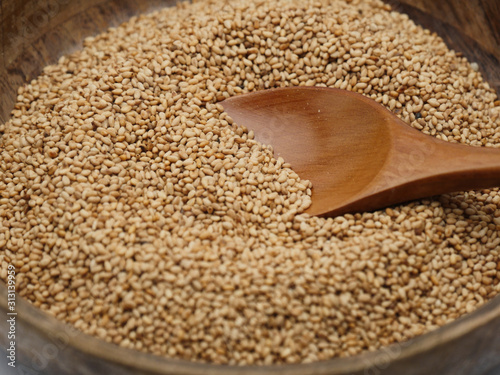 Toasted sesame seeds on wooden bowl with spoon