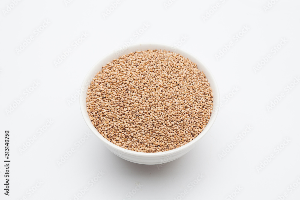 Toasted Sesame seeds in wooden spoon on white Toasted Sesame seeds in wooden spoon on white