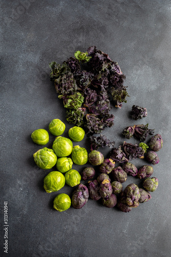 Green and violet brussels sprouts with flower sprout on dark board, top view