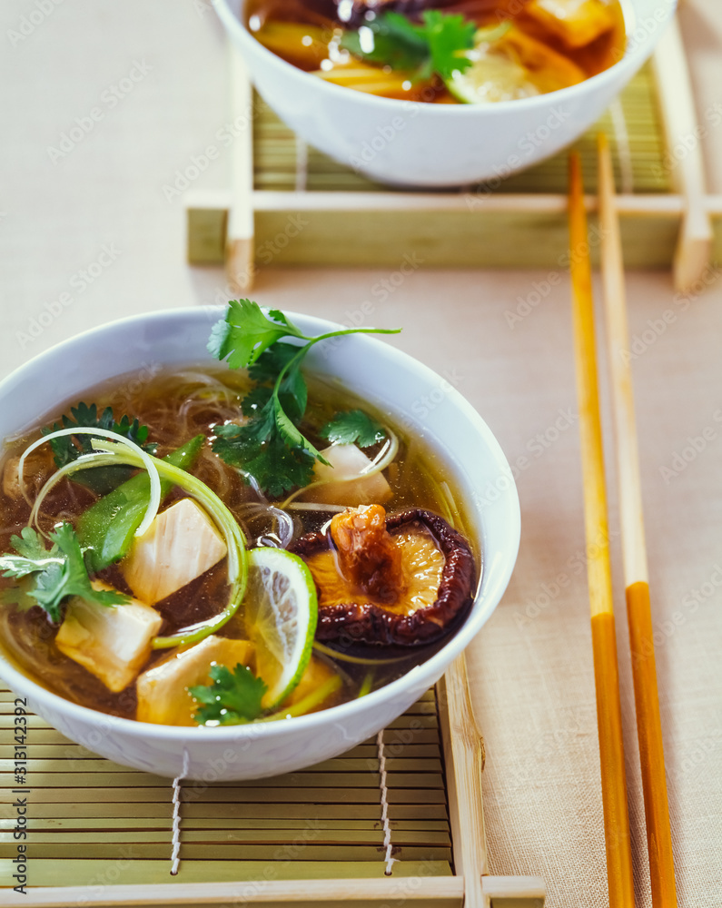 Asiatische Hühnersuppe mit Koriander und Shiitake Pilzen in einer Schüssel Asiatische Hühnersuppe mit Koriander und Shiitake Pilzen in einer Schüssel