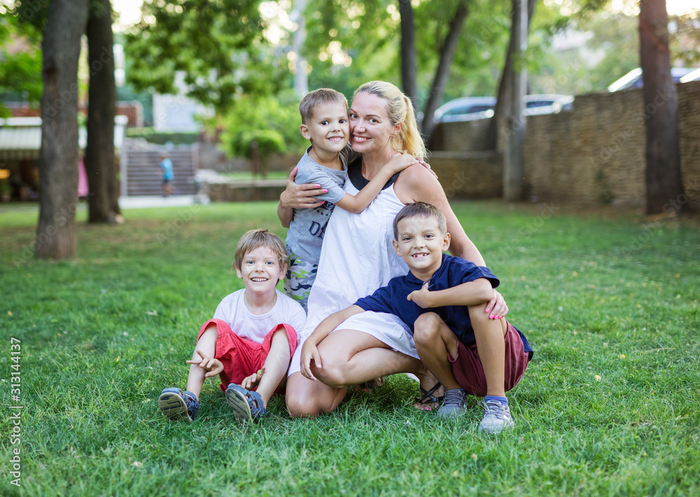 Young woman and three young boys in summer park. Mother and children outdoors. Young woman and three young boys in summer park. Mother and children outdoors.