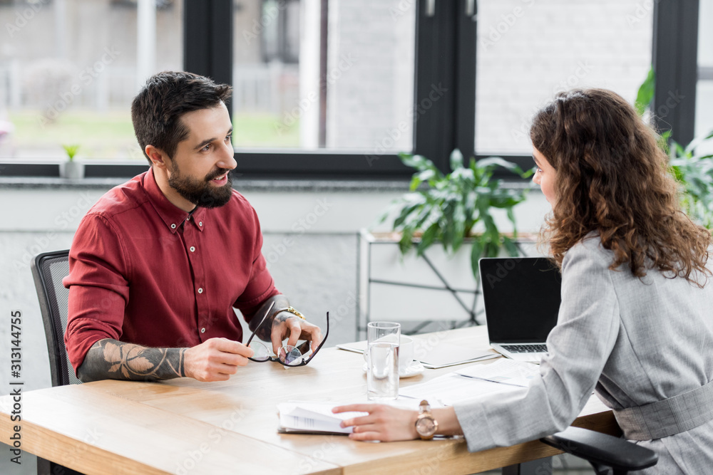 smiling account managers sitting at table and talking in office smiling account managers sitting at table and talking in office