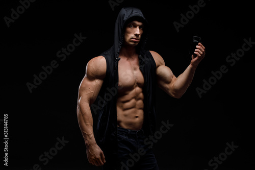 Muscular bodybuilder with jar of protein on a dark background. Sports nutrition. Bodybuilding nutrition supplements, sport, workout, healthy lifestyle concept. © kiy_lg