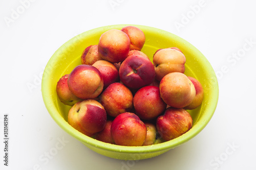 Ripe peaches in a green basket on a white