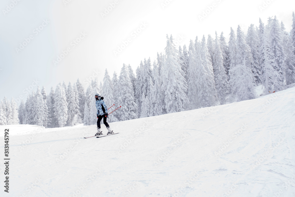 Young woman skiing in mountain resort during winter vacation