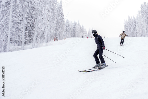 Young man skiing downhill in mountain resort during winter vacation