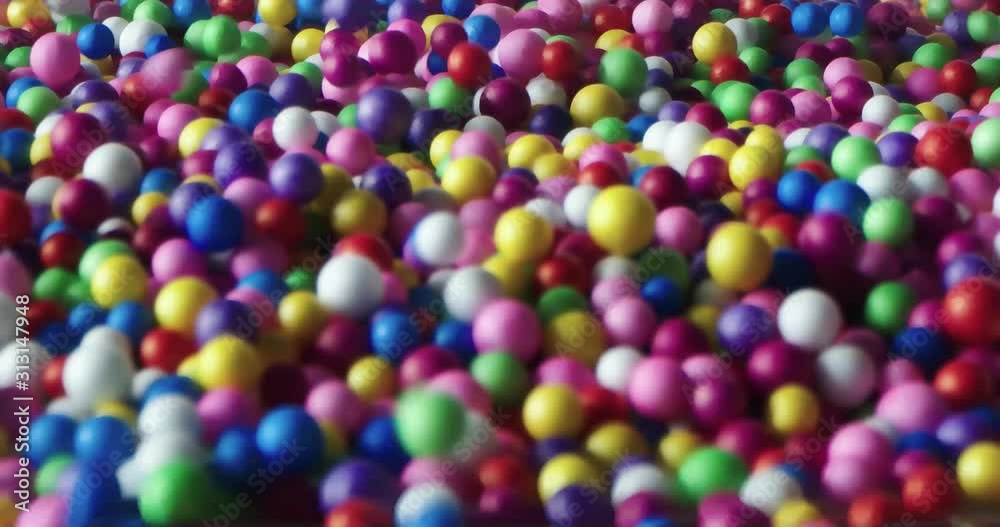 Multi-colored balls falling and scattering in different directions and rolling on a white surface Multi-colored balls falling and scattering in different directions and rolling on a white surface