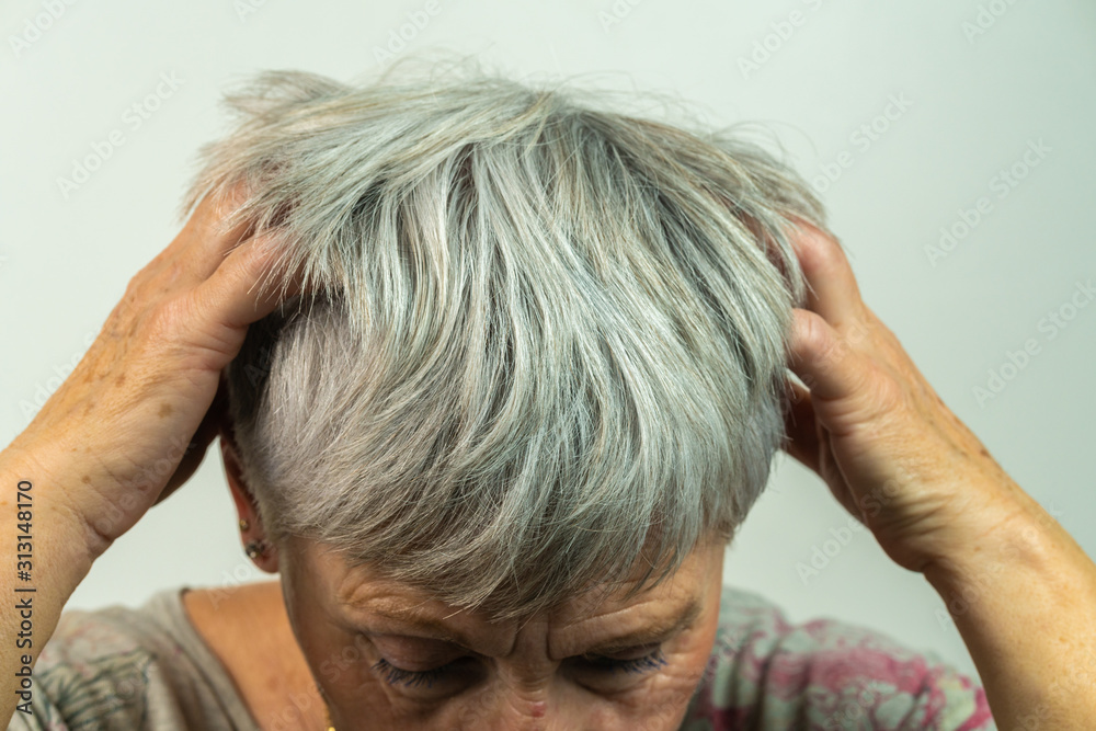 adult White haired woman scratching her head with both hands adult White haired woman scratching her head with both hands