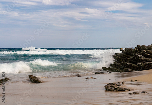 Breaking waves on sandy coast with rocks