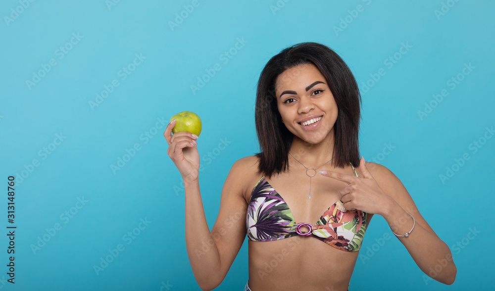 Pretty young woman keeping in hand fresh green apple on blue isolated background. Cool female posing and laughing while eating useful fruits. Pretty young woman keeping in hand fresh green apple on blue isolated background. Cool female posing and laughing while eating useful fruits.