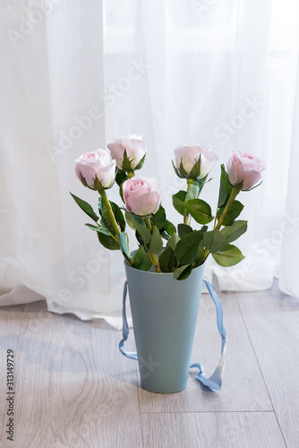 Fototapeta Naklejka Na Ścianę i Meble -  Beautiful bouquet of pink roses in a gift blue box on the floor near the window and curtains