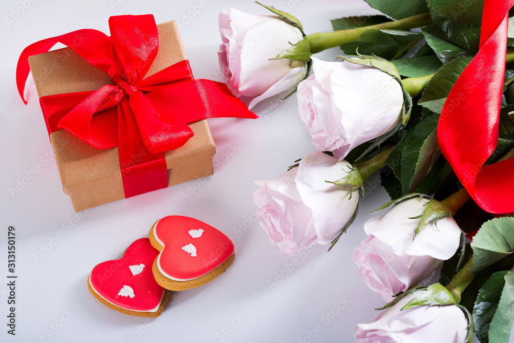Homemade Valentines day heart cookies, pink roses and red gift box on white table Homemade Valentines day heart cookies, pink roses and red gift box on white table