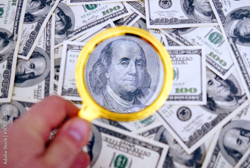 One hundred dollars banknote under magnifier.