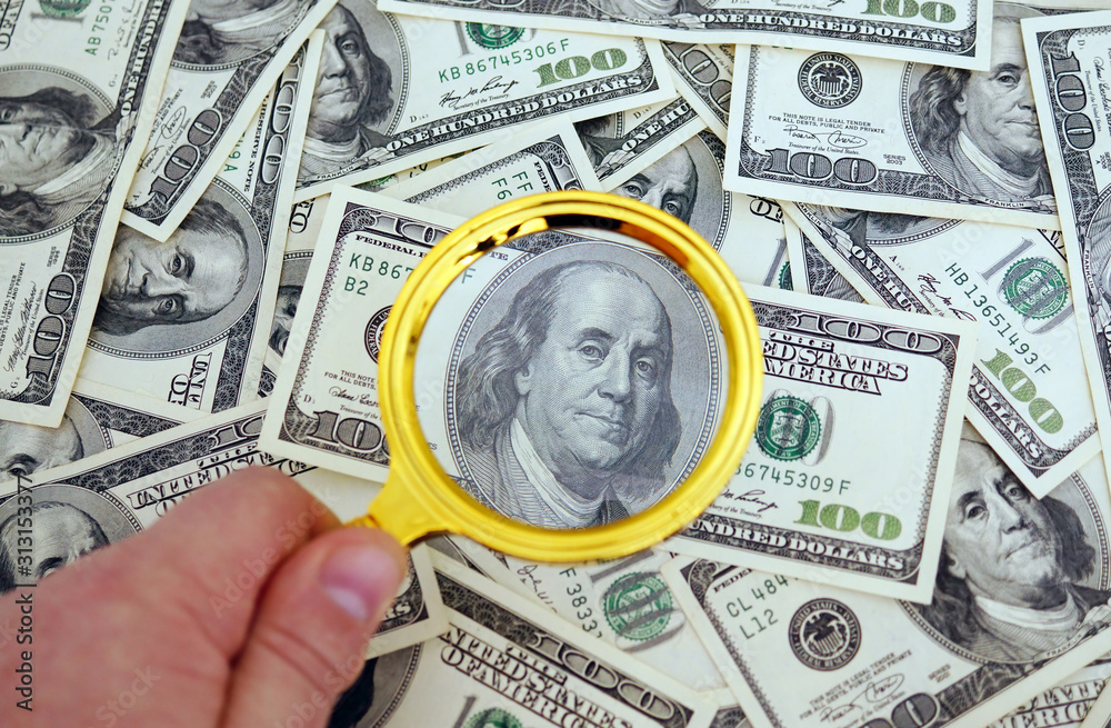 One hundred dollars banknote under magnifier.