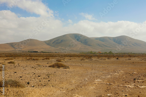 Arid region dry soil with rounded mountains on the background panoramic view on Furteventura Island