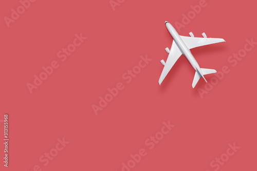 Flat lay of miniature toy airplane on red background
