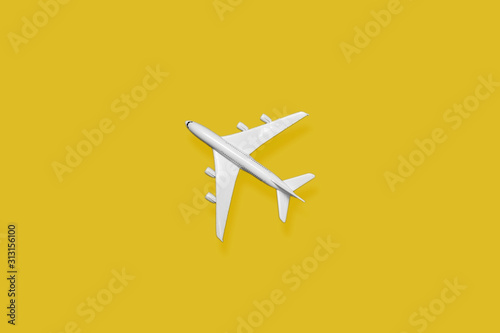 Flat lay of miniature toy airplane on yellow background
