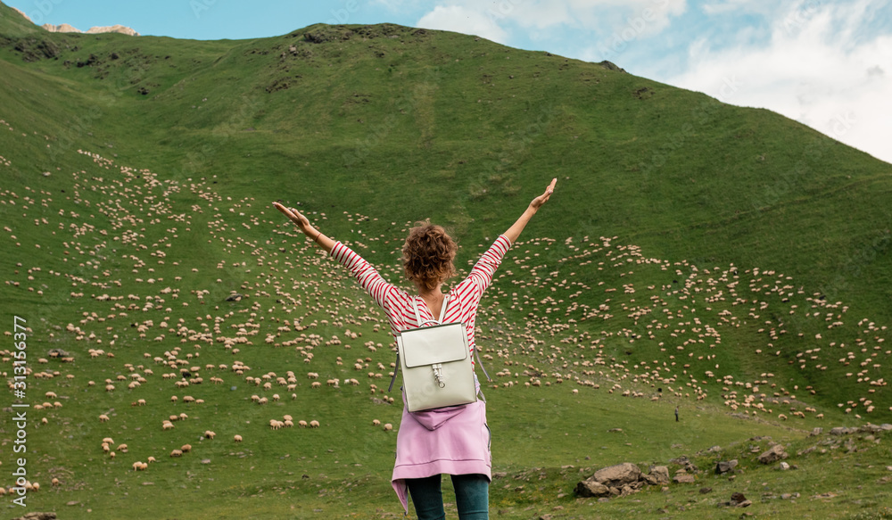 Curly woman happy smiling joyful with arms up dancing on field with sheeps Curly woman happy smiling joyful with arms up dancing on field with sheeps