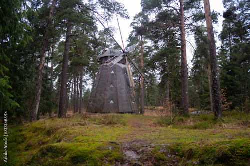 An old authentic wooden mill of the 18th century worked until 1960, located in a forest on the island of Seurasaari in Helsinki, Finland, a cloudy day in late autumn. photo