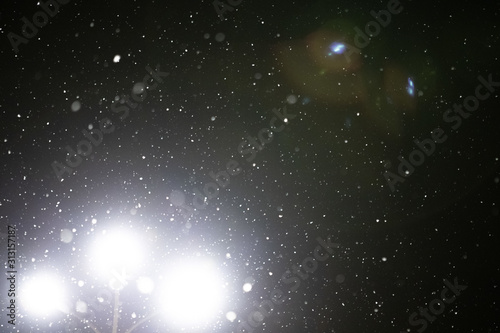 Snow and bokeh in the light of a lantern on a black background