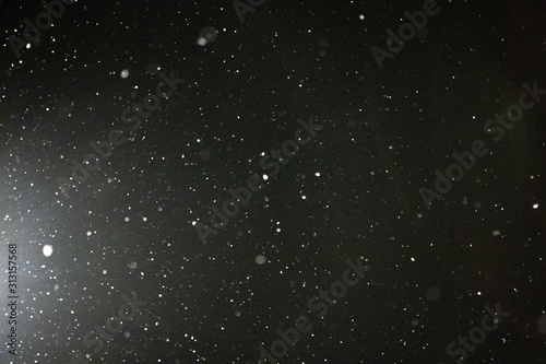 Snow and bokeh in the light of a lantern on a black background