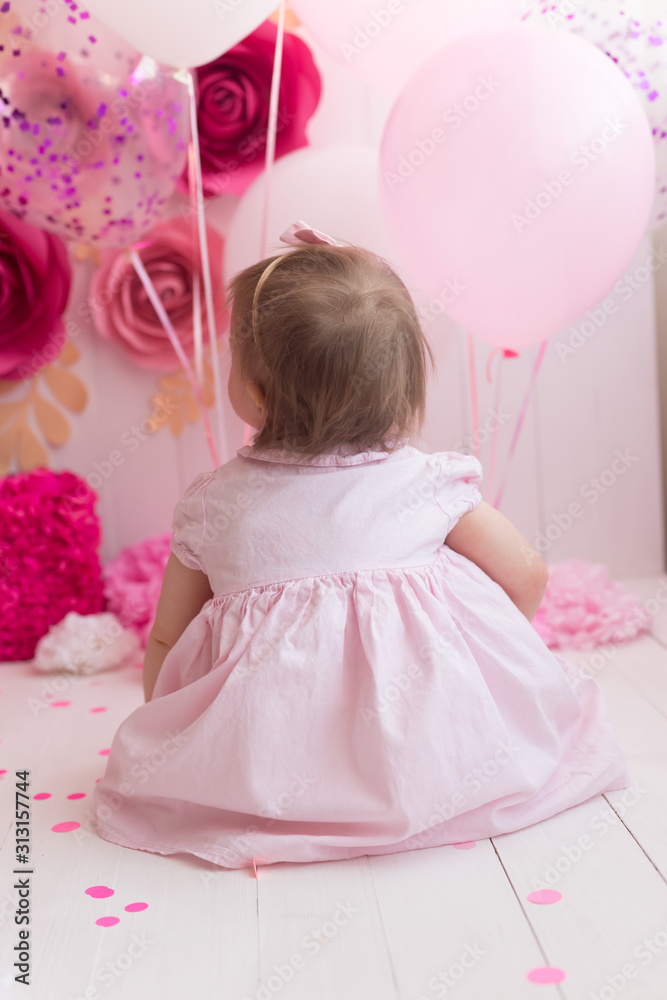 a little girl is sitting with her back against the background of a large unit and pink balls a little girl is sitting with her back against the background of a large unit and pink balls