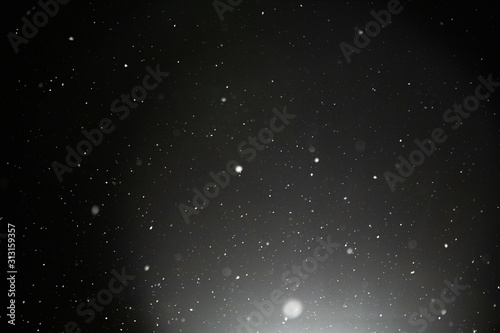 Snow and bokeh in the light of a lantern on a black background