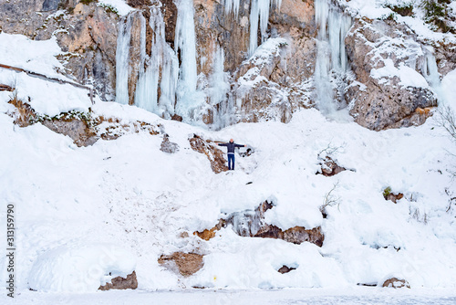 man walks on frozen lake Braies in Italy in winter, concept of winter travel