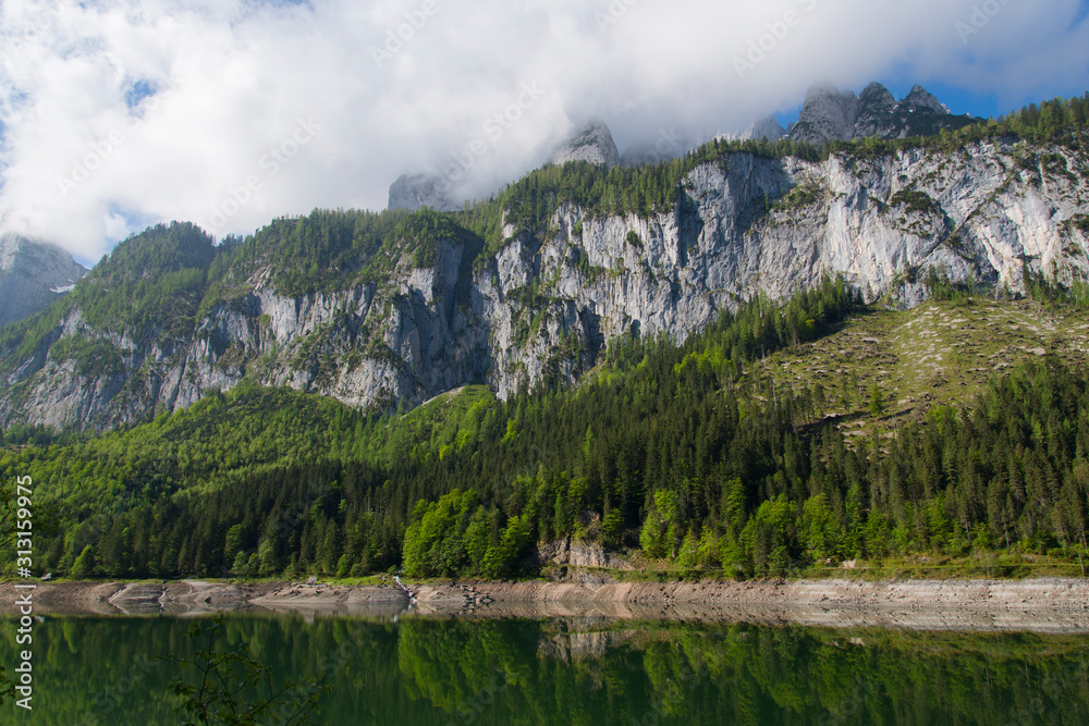 rock face with clouds over lake gosau